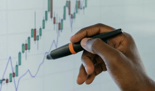 Hand using a stylus on a financial data chart